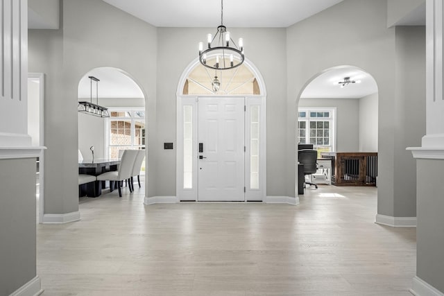 foyer entrance with a chandelier, a wealth of natural light, and light wood-style floors