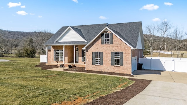 view of front of home with a porch, brick siding, concrete driveway, a gate, and a front yard