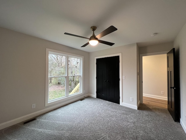 unfurnished bedroom with dark carpet, a closet, and ceiling fan