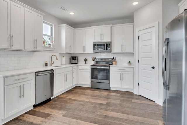 kitchen featuring appliances with stainless steel finishes, dark hardwood / wood-style floors, sink, and white cabinets