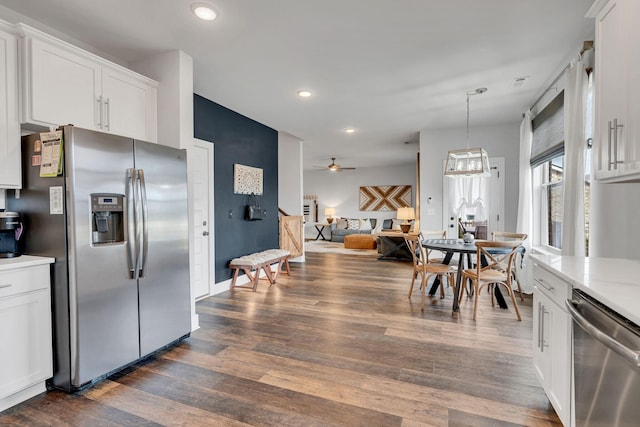 kitchen featuring dark wood-type flooring, ceiling fan, appliances with stainless steel finishes, white cabinetry, and decorative light fixtures