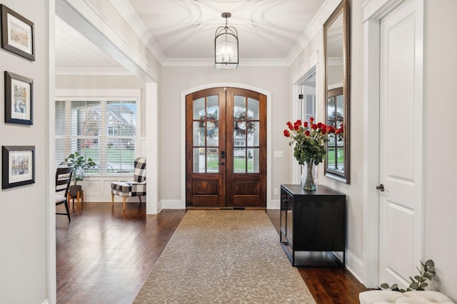 entrance foyer featuring ornamental molding, dark wood-type flooring, a notable chandelier, and french doors