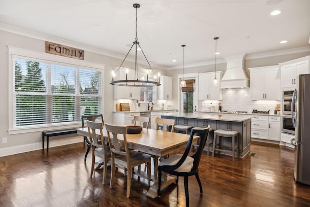 dining space featuring sink, crown molding, and dark wood-type flooring