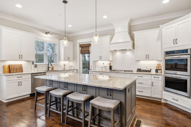 kitchen with white cabinetry, pendant lighting, stainless steel appliances, and a kitchen island