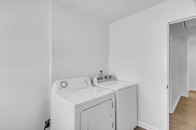 clothes washing area featuring washer and dryer and light wood-type flooring