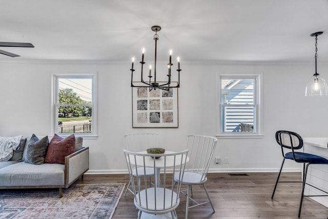 dining area with dark wood-type flooring, ornamental molding, and a healthy amount of sunlight