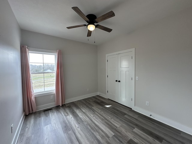 unfurnished room with a ceiling fan, wood finished floors, visible vents, and baseboards