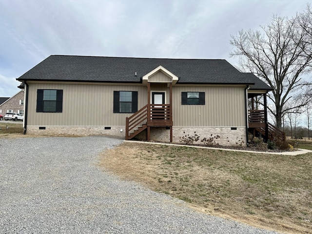 view of front of property with crawl space, roof with shingles, and gravel driveway