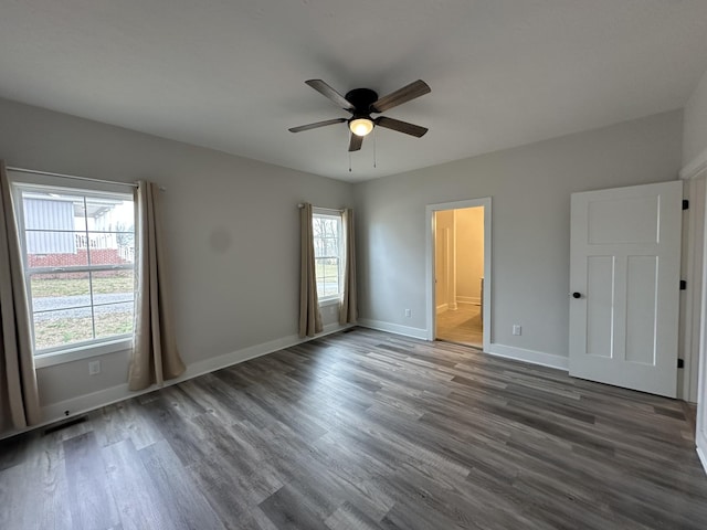 unfurnished bedroom with visible vents, baseboards, ensuite bath, ceiling fan, and wood finished floors