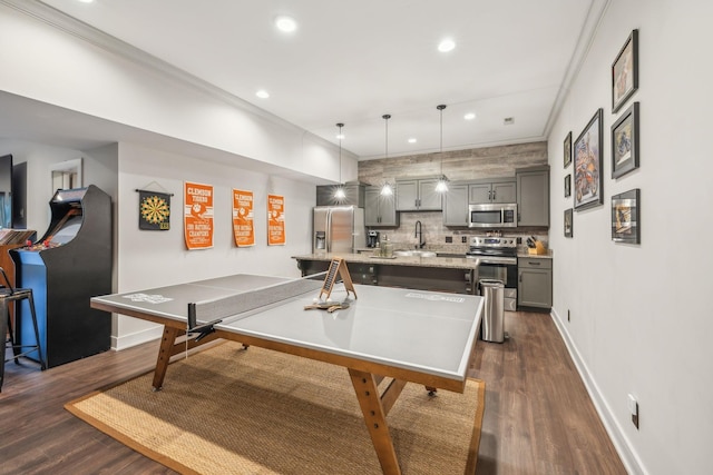 playroom with recessed lighting, a sink, baseboards, ornamental molding, and dark wood-style floors