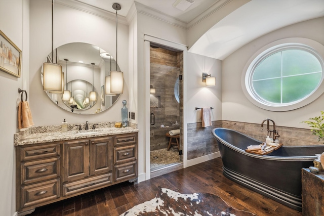 bathroom featuring wood finished floors, vanity, visible vents, a shower stall, and crown molding