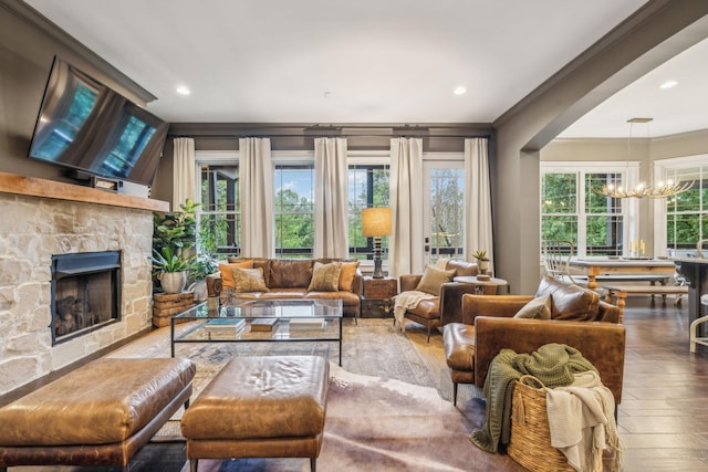 living room featuring a chandelier, a stone fireplace, recessed lighting, wood finished floors, and ornamental molding