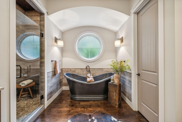 bathroom with a soaking tub, wainscoting, baseboards, and wood finished floors