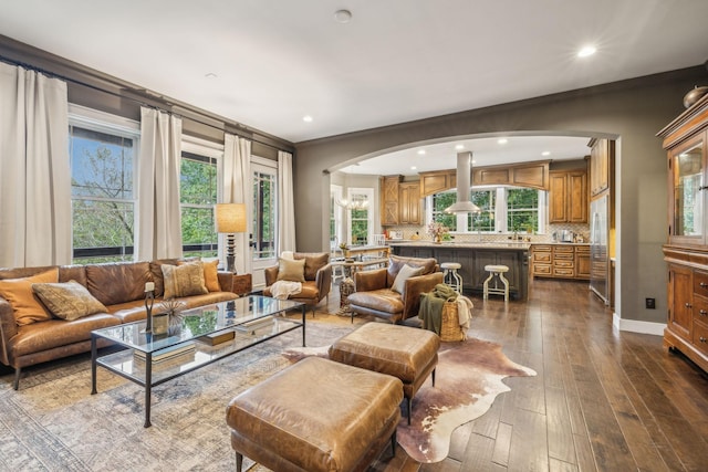 living room featuring dark wood-type flooring, recessed lighting, arched walkways, and baseboards