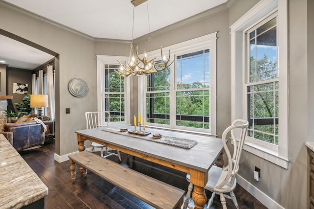 dining room featuring a chandelier, dark wood-style flooring, crown molding, and baseboards