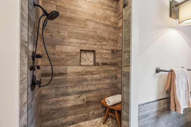 full bath featuring a tile shower and wood walls