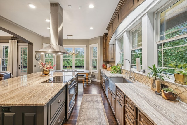 kitchen with stainless steel electric range oven, light stone counters, a center island, island exhaust hood, and a sink