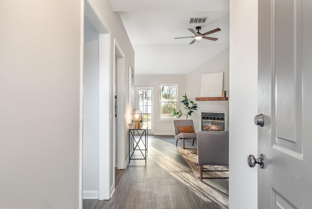 hall featuring lofted ceiling, visible vents, baseboards, and wood finished floors