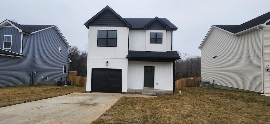 rear view of house featuring a garage, a lawn, and central air condition unit