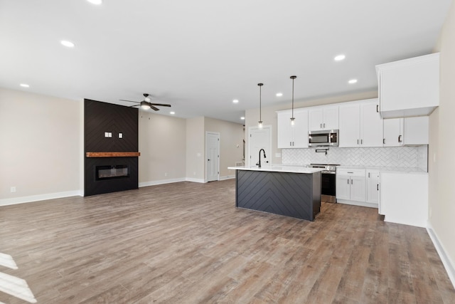 kitchen featuring a large fireplace, appliances with stainless steel finishes, decorative backsplash, and light countertops