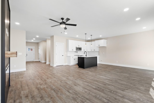 unfurnished living room with recessed lighting, ceiling fan, baseboards, and wood finished floors