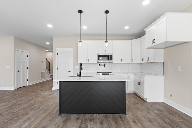 kitchen with dark wood-style floors, tasteful backsplash, stainless steel microwave, visible vents, and a sink