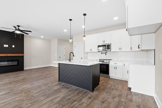 kitchen featuring stainless steel appliances, light countertops, a fireplace, and decorative backsplash