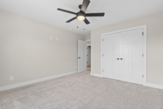 unfurnished bedroom featuring light carpet, a ceiling fan, baseboards, and a closet