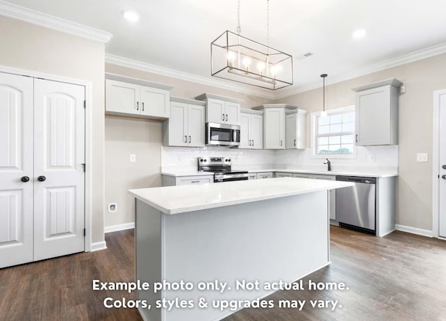 kitchen featuring hanging light fixtures, ornamental molding, stainless steel appliances, and a kitchen island