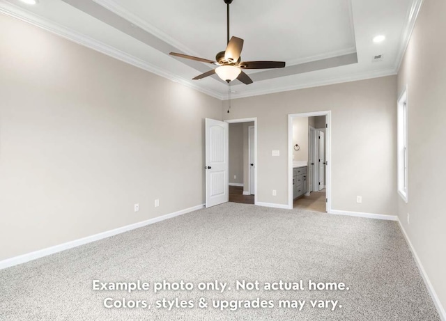 unfurnished bedroom with ornamental molding, connected bathroom, light colored carpet, and a tray ceiling