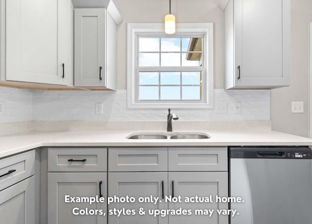 kitchen featuring pendant lighting, sink, stainless steel dishwasher, and backsplash