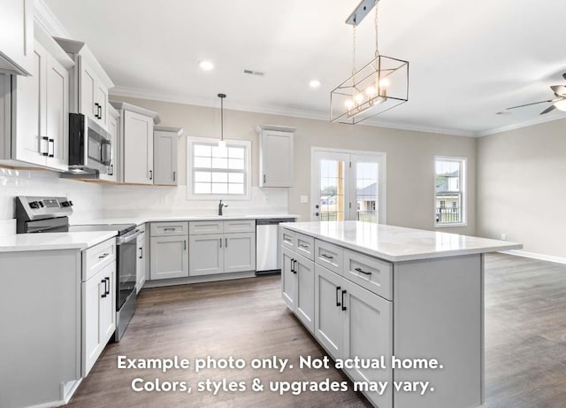 kitchen featuring pendant lighting, a kitchen island, plenty of natural light, and appliances with stainless steel finishes