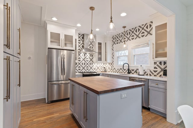 kitchen featuring pendant lighting, butcher block countertops, gray cabinetry, stainless steel appliances, and a kitchen island