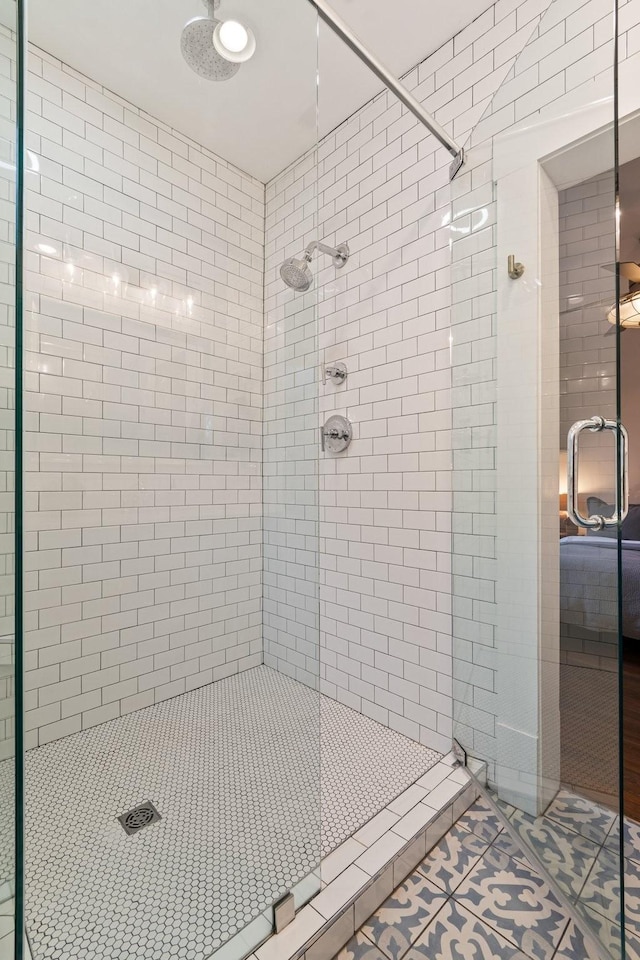 bathroom with a shower with door and tile patterned flooring