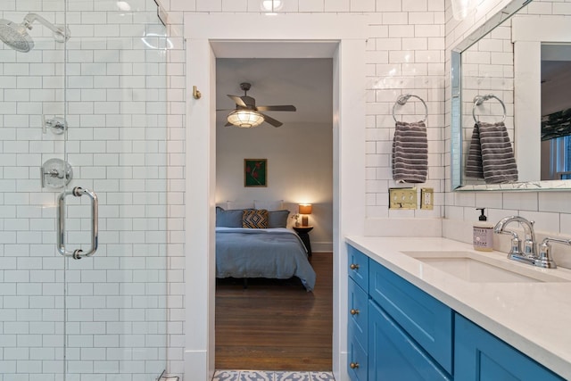 bathroom with wood-type flooring, backsplash, vanity, ceiling fan, and a shower with door