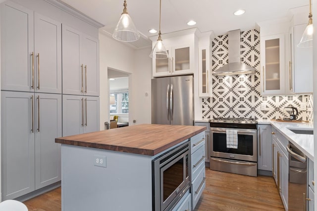 kitchen with hanging light fixtures, a center island, wood counters, and stainless steel appliances