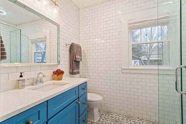 bathroom with tile walls, vanity, plenty of natural light, and toilet