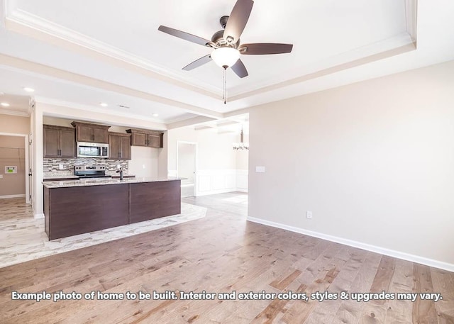 kitchen featuring crown molding, light hardwood / wood-style flooring, appliances with stainless steel finishes, tasteful backsplash, and a tray ceiling