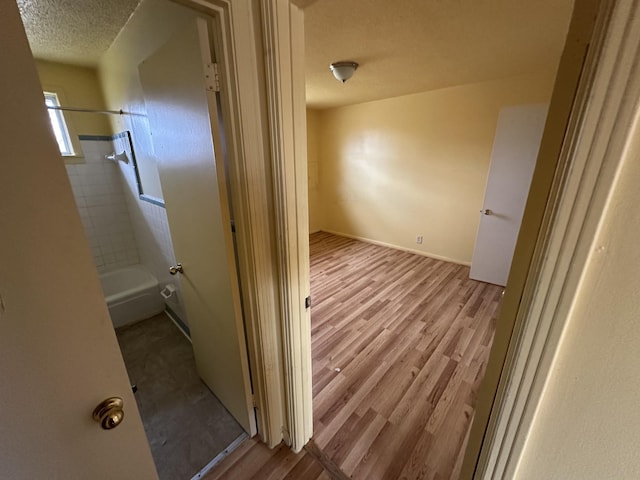 hall with light hardwood / wood-style floors and a textured ceiling