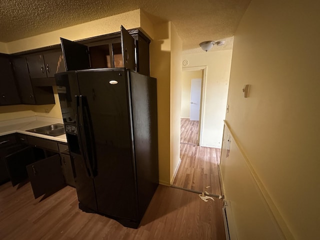 kitchen featuring black fridge, sink, a textured ceiling, and light hardwood / wood-style floors