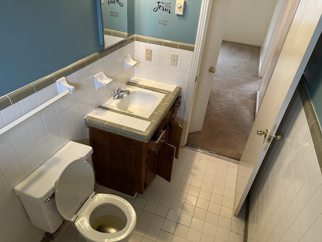 bathroom with tile patterned flooring, vanity, tile walls, and toilet