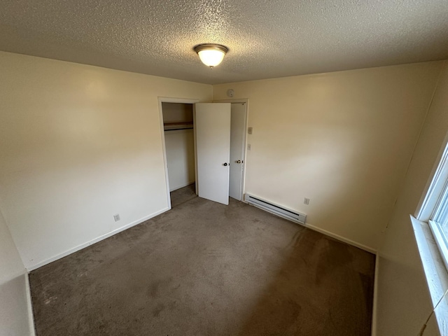 unfurnished bedroom with dark carpet, a closet, a textured ceiling, and baseboard heating