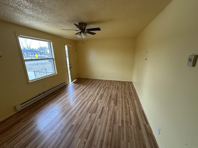 spare room with ceiling fan, a textured ceiling, baseboard heating, and light hardwood / wood-style flooring