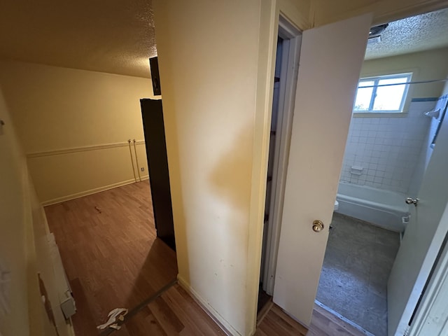 bathroom with hardwood / wood-style flooring, tiled shower / bath, and a textured ceiling