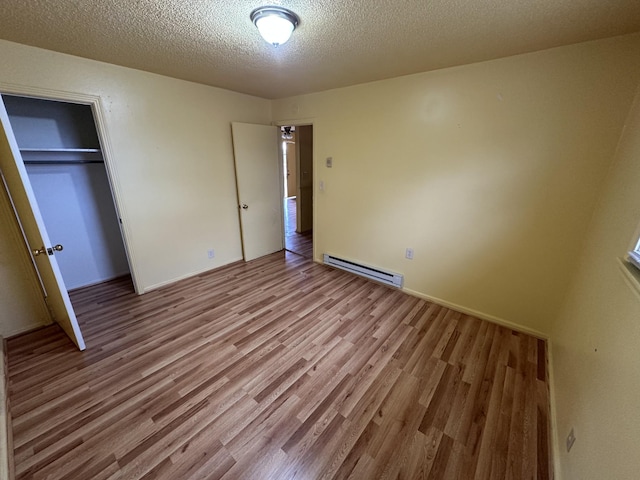 unfurnished bedroom with light hardwood / wood-style flooring, a baseboard radiator, a closet, and a textured ceiling