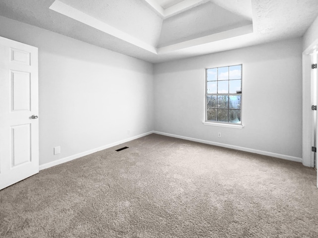 carpeted empty room with a textured ceiling and a tray ceiling