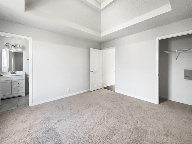 unfurnished bedroom featuring a tray ceiling, carpet floors, and a textured ceiling