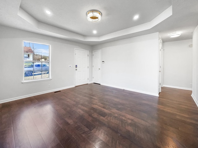 unfurnished room with dark hardwood / wood-style floors and a tray ceiling