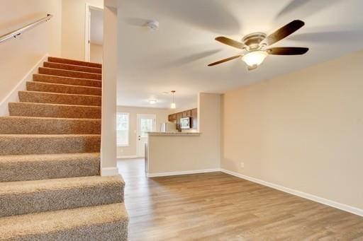 stairs featuring ceiling fan and hardwood / wood-style floors