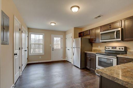 kitchen with light stone countertops, appliances with stainless steel finishes, dark brown cabinets, and dark wood-type flooring